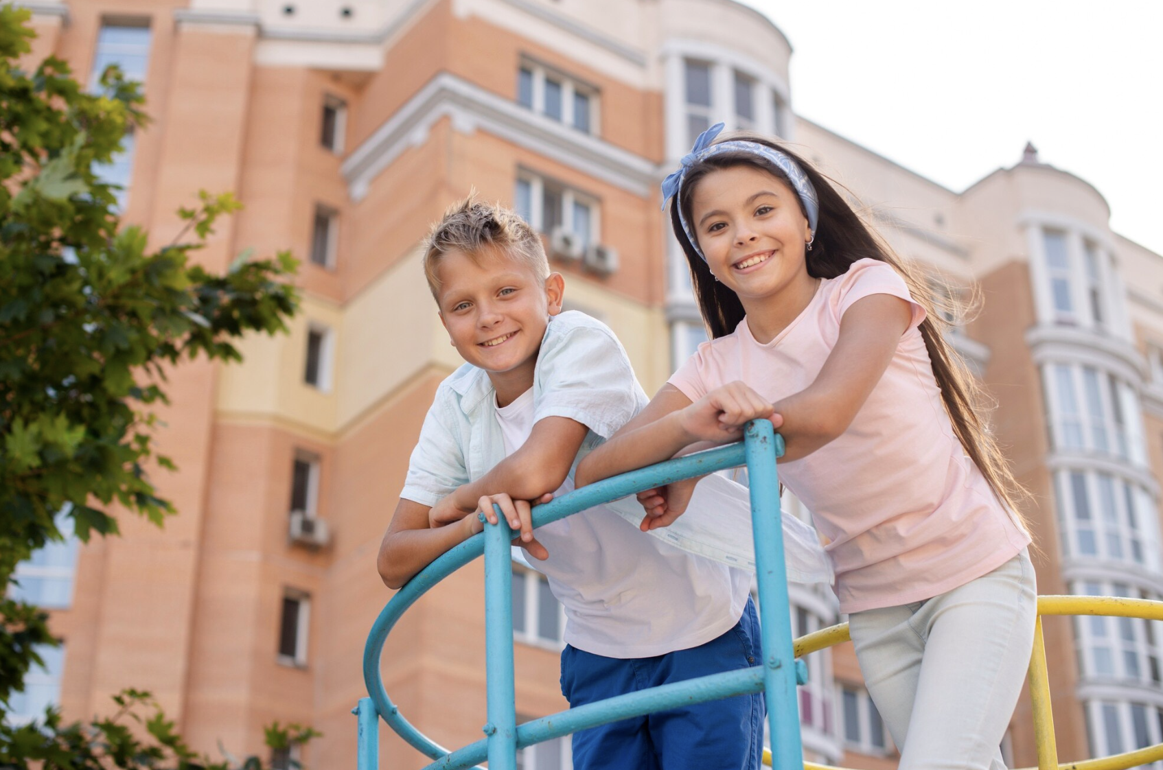 Two students leaning on a railing outside a school building